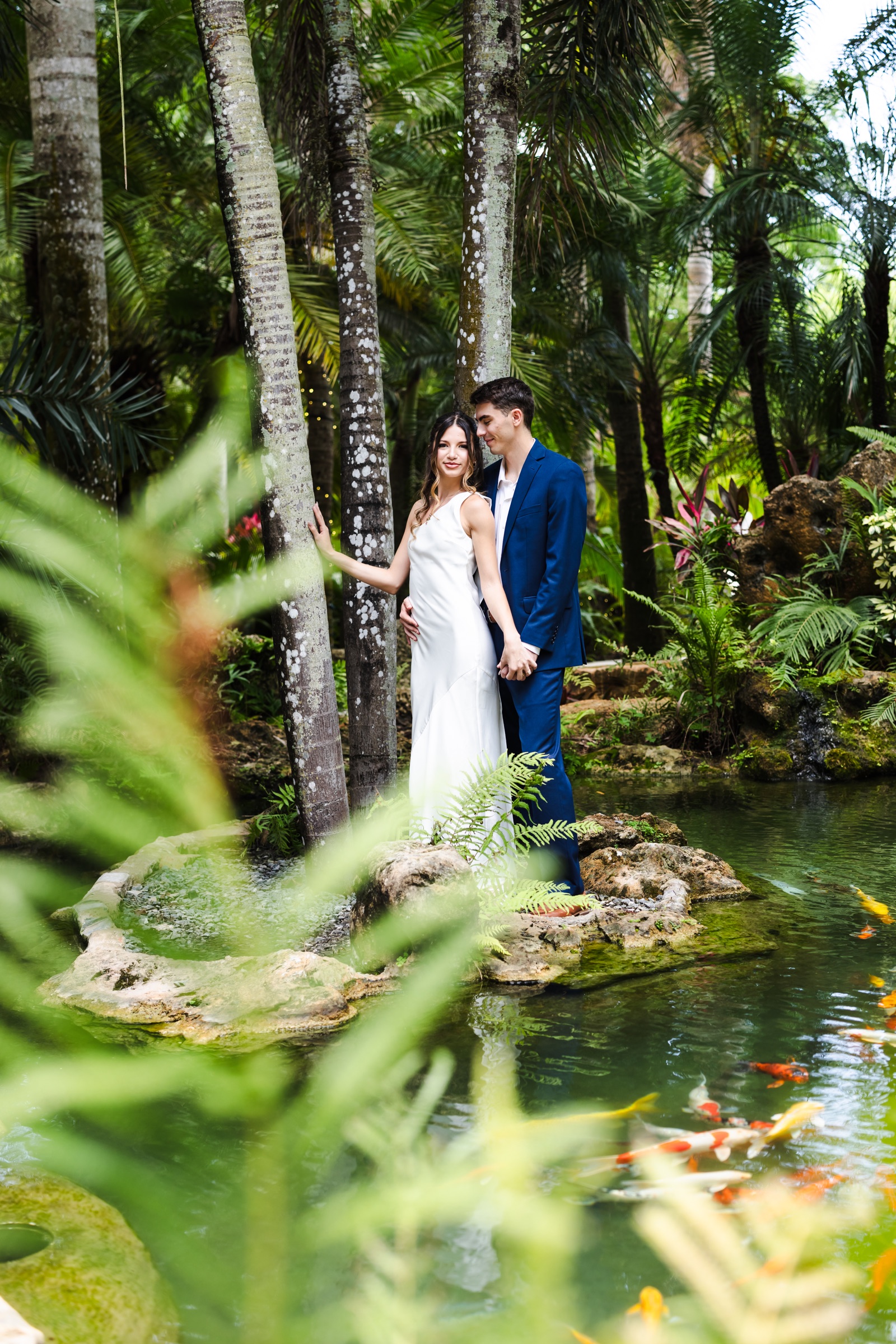 A couple together in a tropical garden beside a koi pond