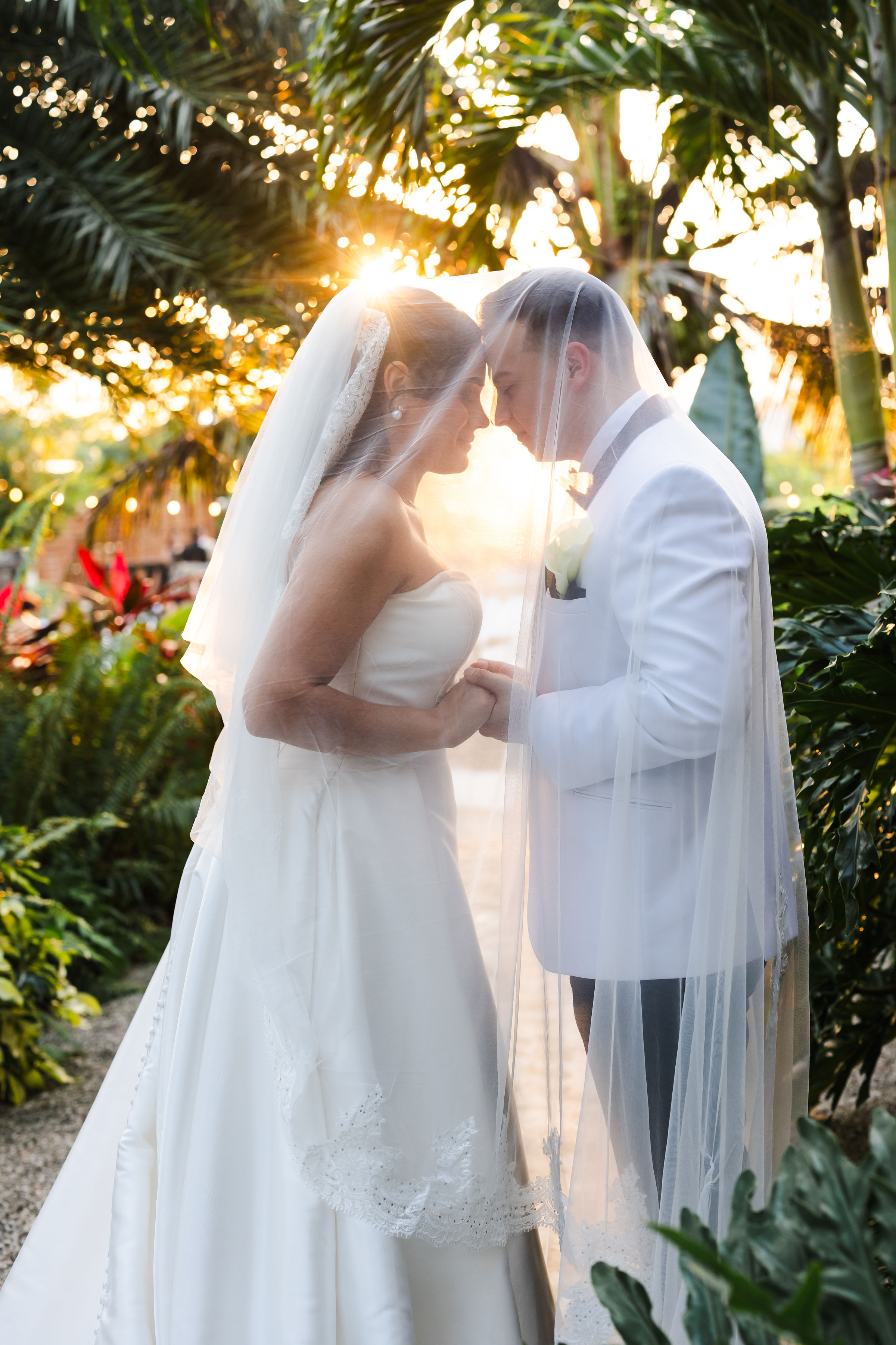 Ana and Pablo sharing a sunset portrait beneath Ana's veil at ElopeWe in Miami