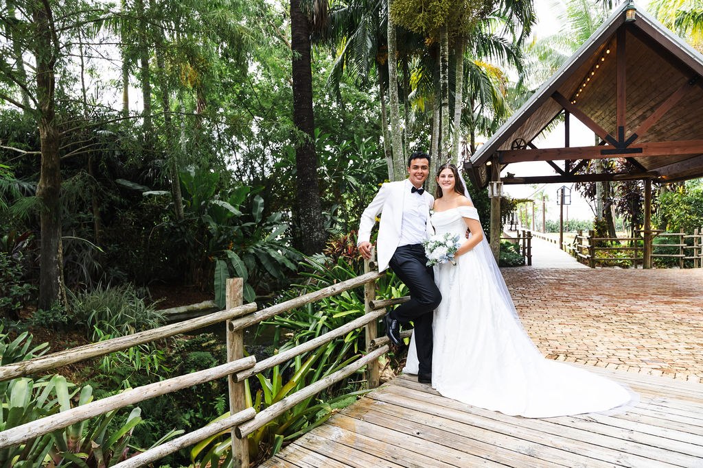 Leah and Jose together on a wooden bridge beside a garden pavilion