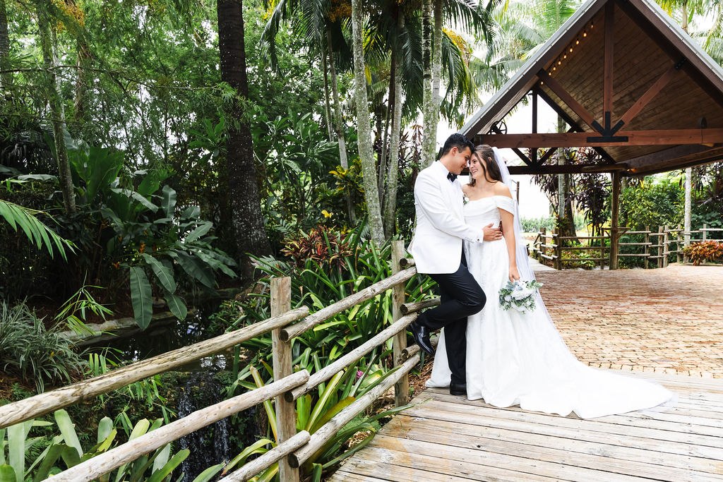 Leah and Jose kissing on the bridge beneath the trees