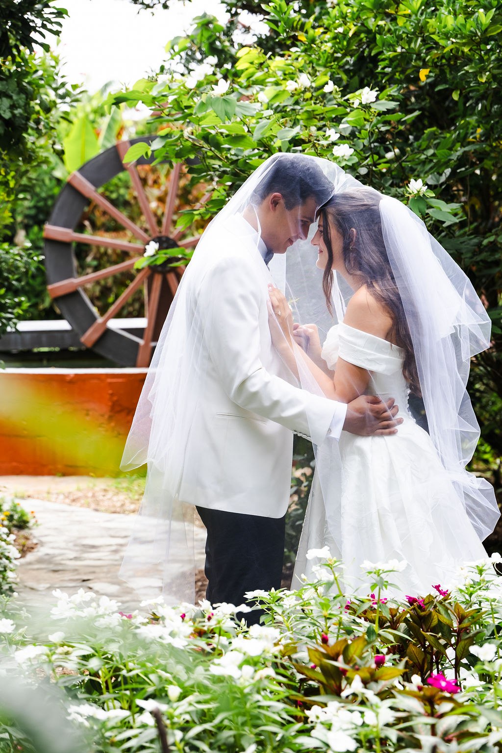 Leah and Jose sharing a close portrait beneath the veil in the garden