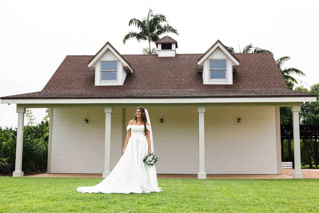 Leah in her wedding dress on the lawn in front of an estate building