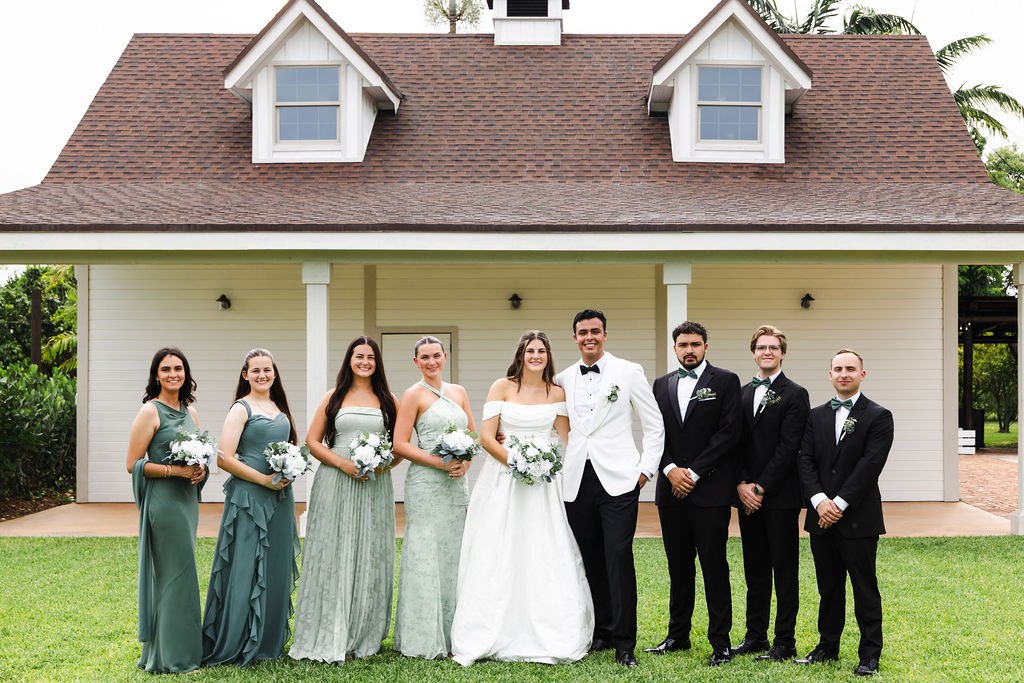 Leah, Jose and their wedding party in front of an estate building