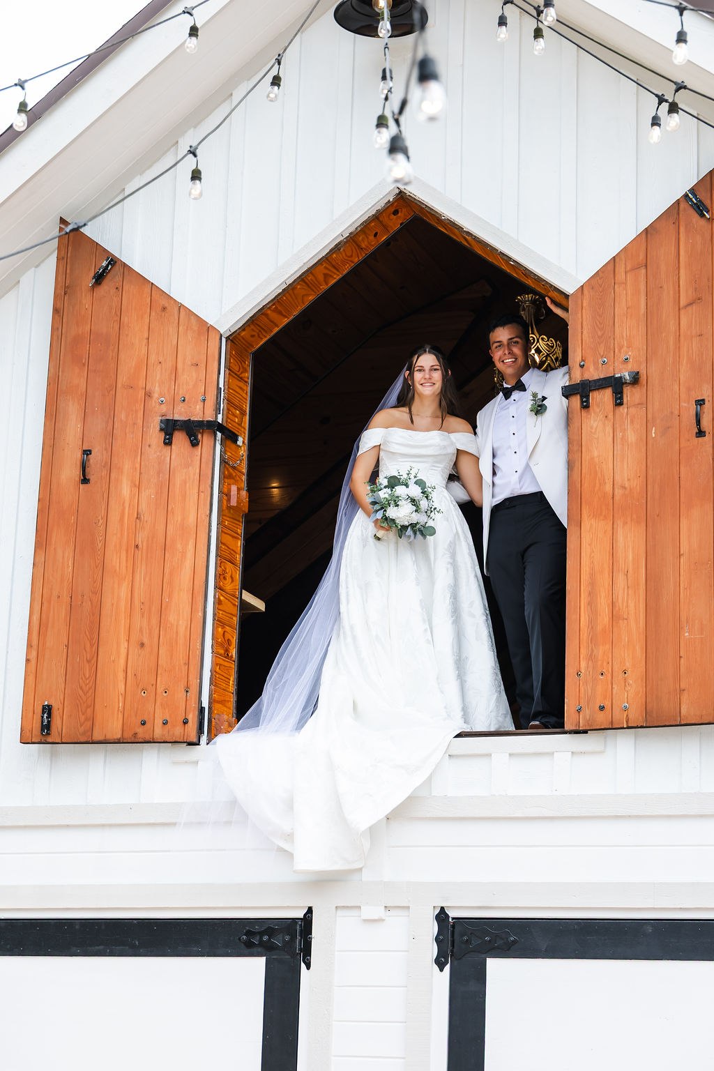 Leah and Jose posing together at the upper opening of the white barn