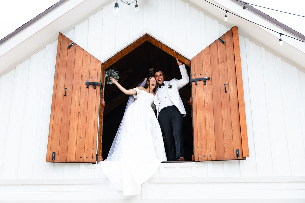 Leah and Jose celebrating at the open wooden barn shutters