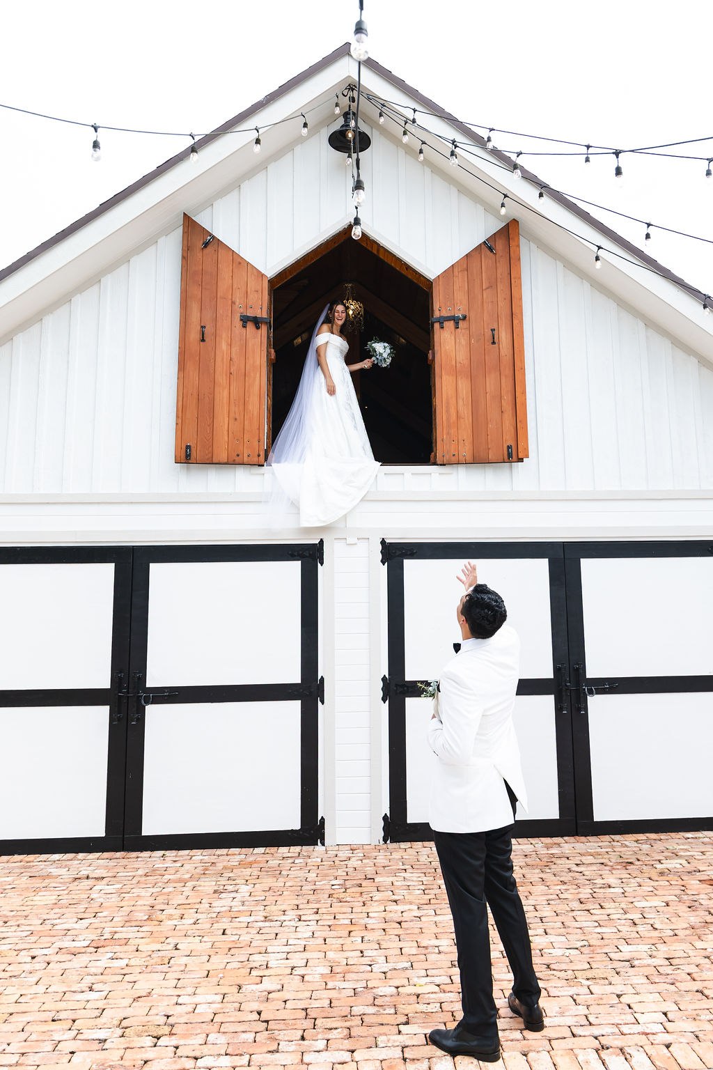 Jose standing outside the barn while Leah looks out from above
