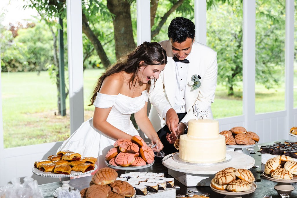 Leah and Jose cutting their wedding cake together
