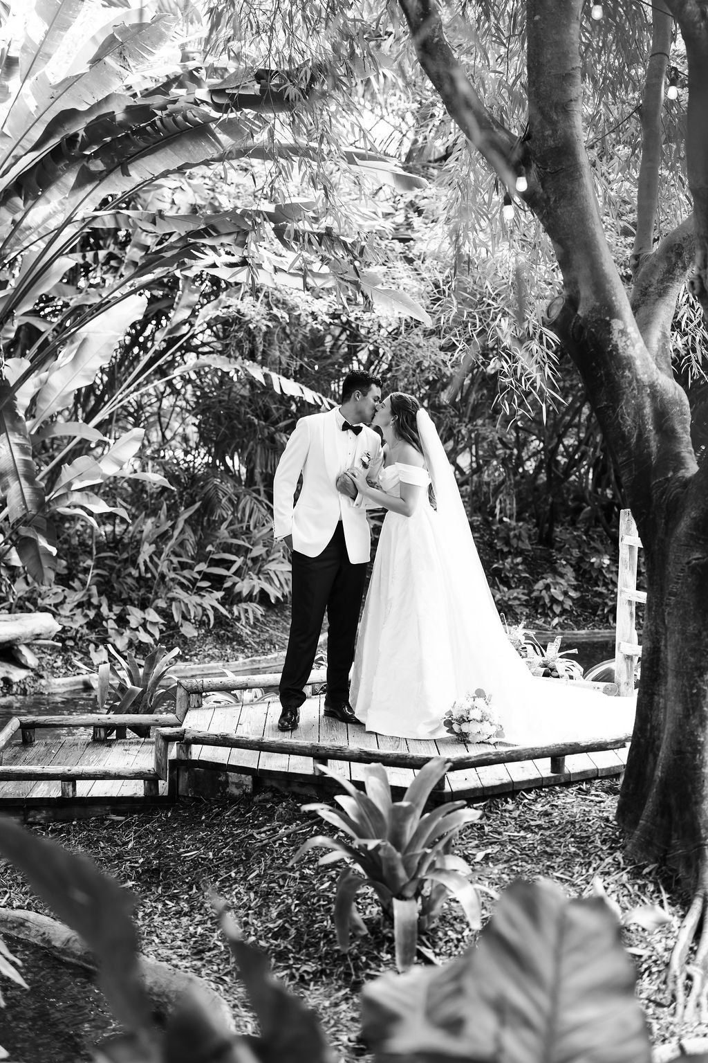 Black-and-white portrait of Leah and Jose standing on a garden bridge