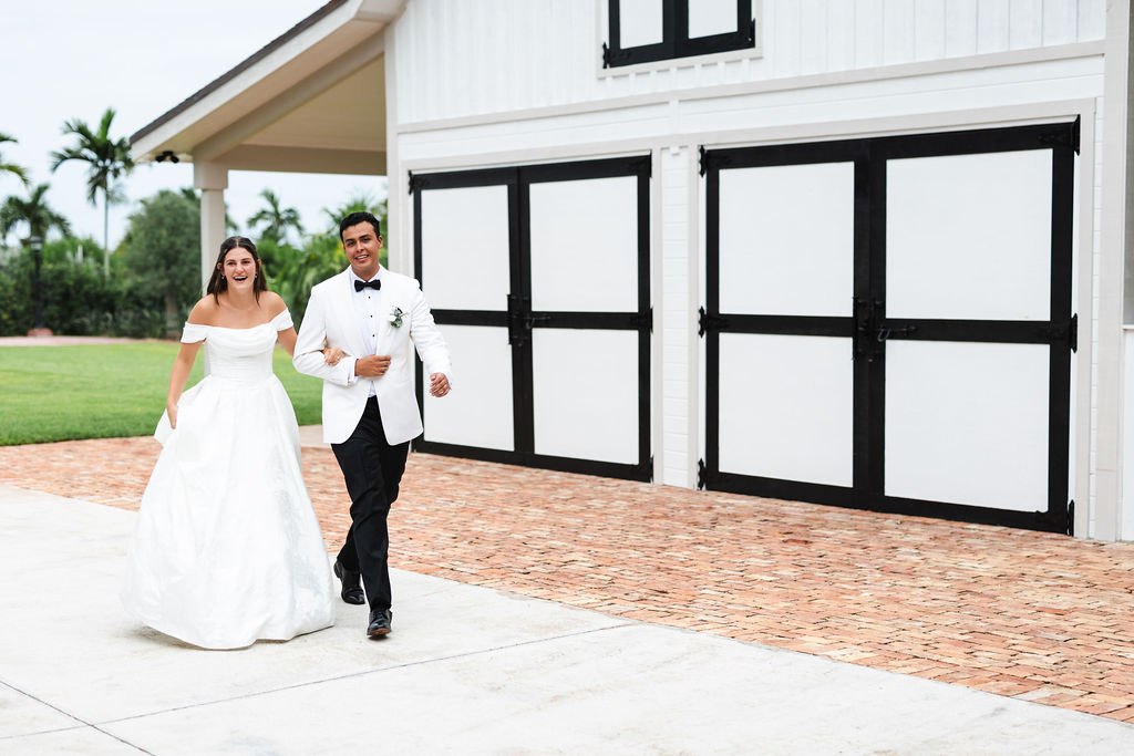 Leah and Jose walking together outside the white barn with black trim