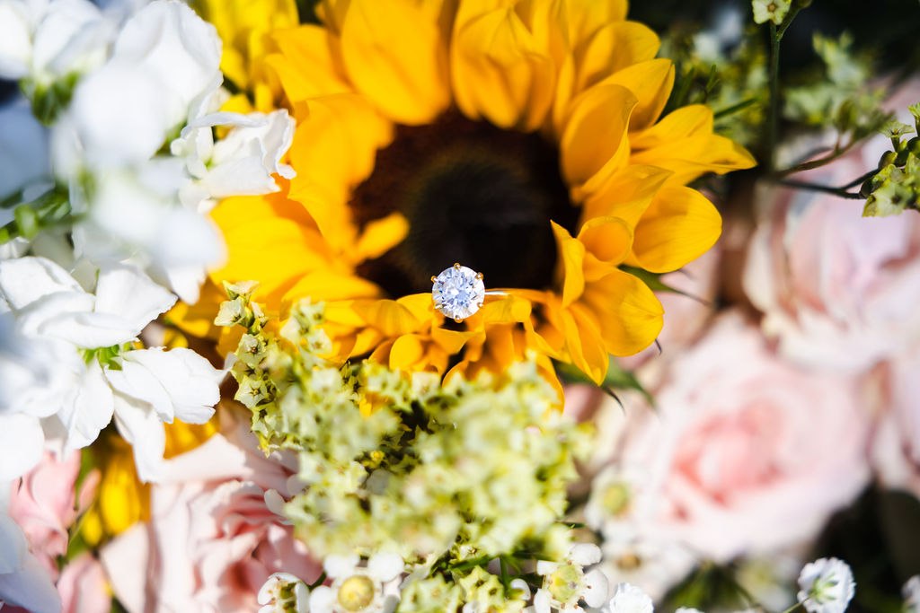 An engagement ring nestled into a sunflower