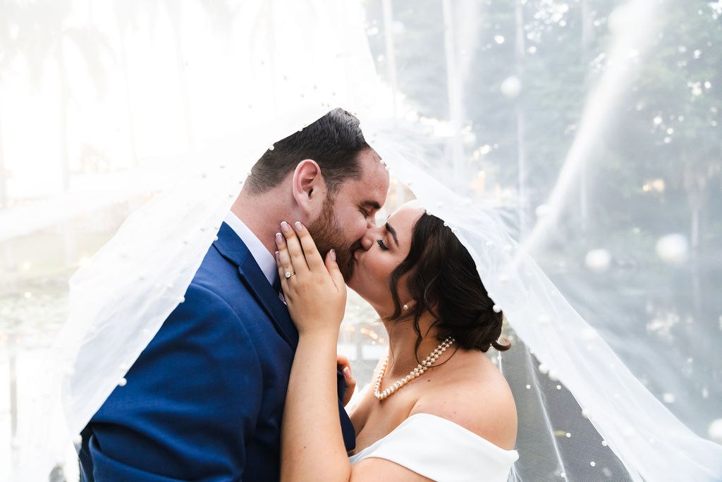 Sara and Brett sharing a kiss beneath the veil