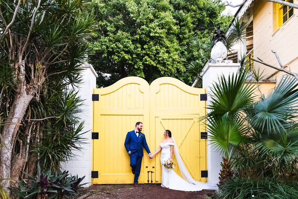 Sara and Brett posing beside the yellow garden gates
