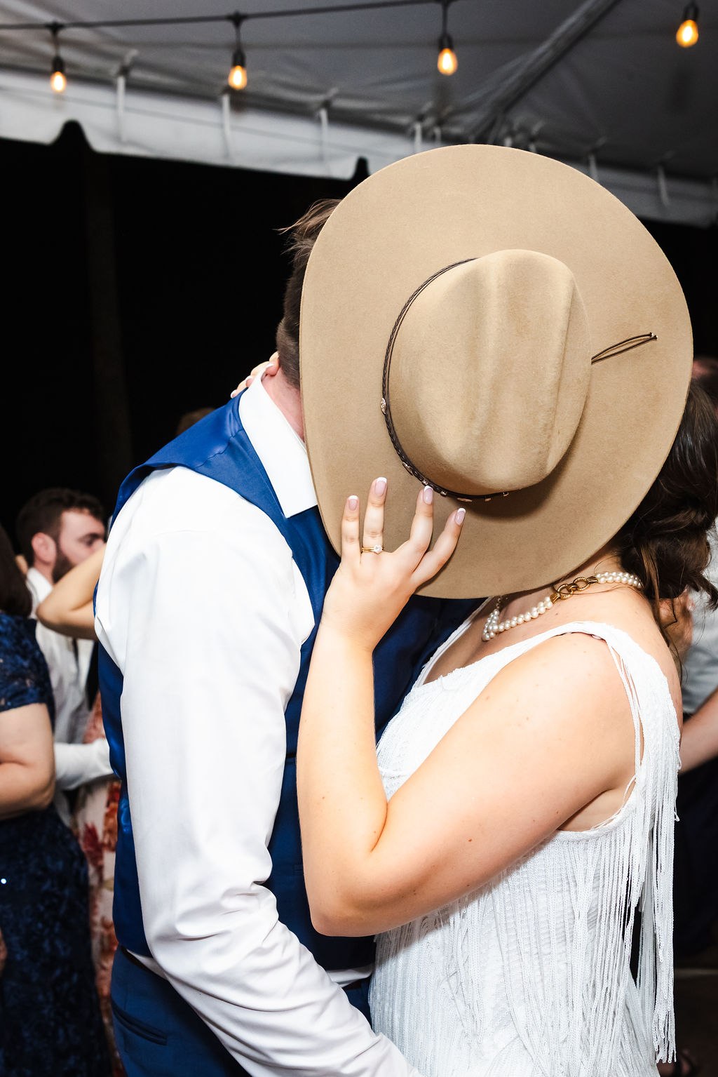 Sara and Brett sharing an evening kiss behind a cowboy hat