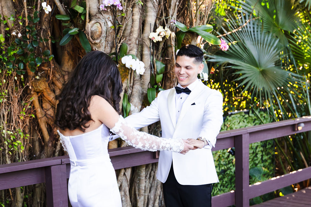 Bryn and Edward holding hands during their first look beneath orchid-covered trees