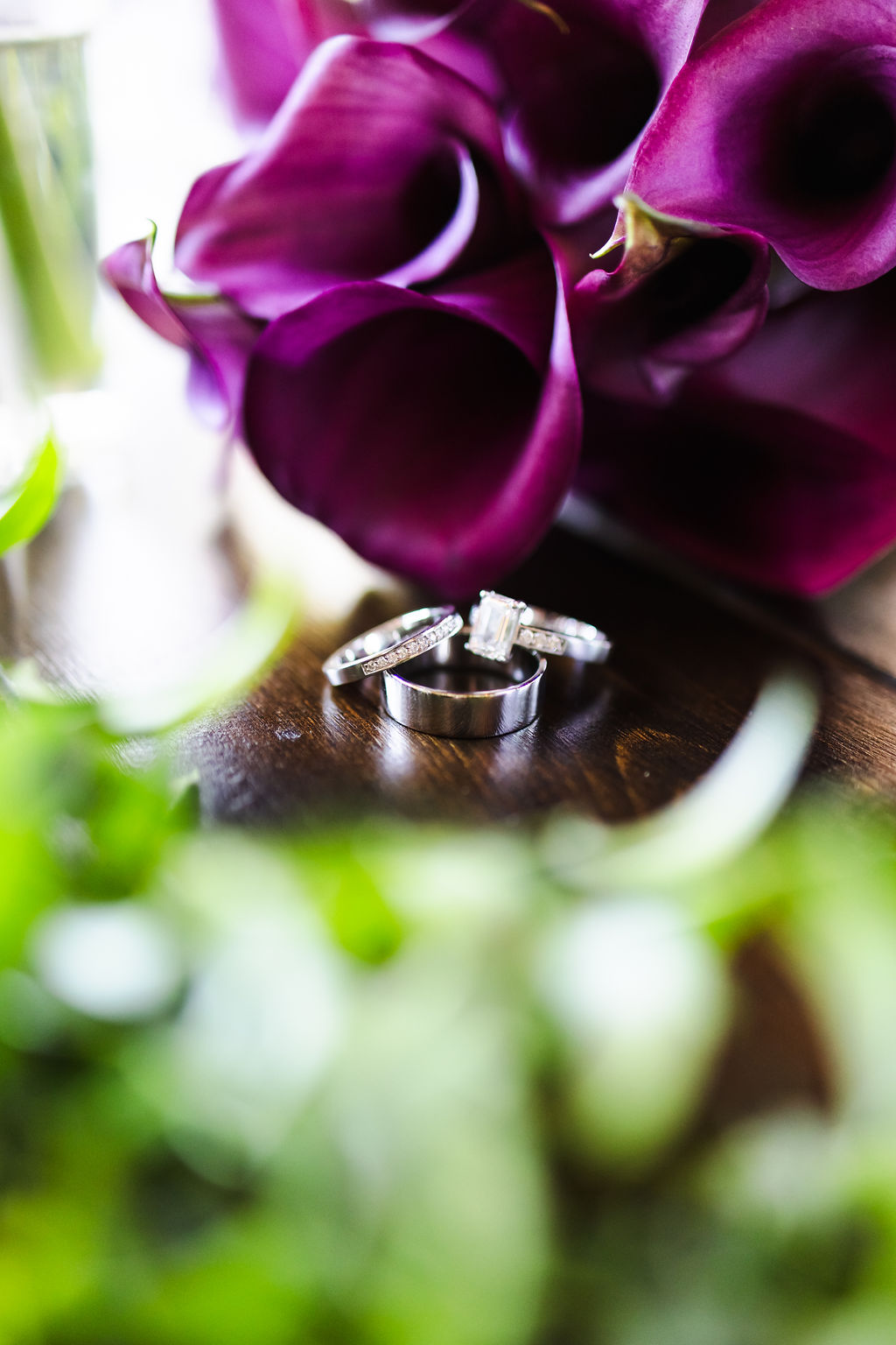 Wedding rings framed by deep purple calla lilies