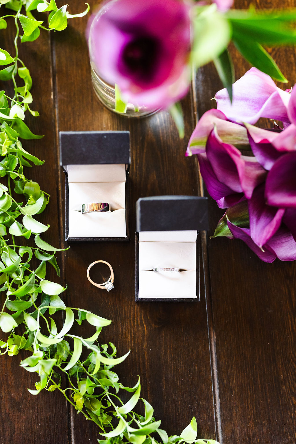 Wedding rings arranged with purple calla lilies and greenery