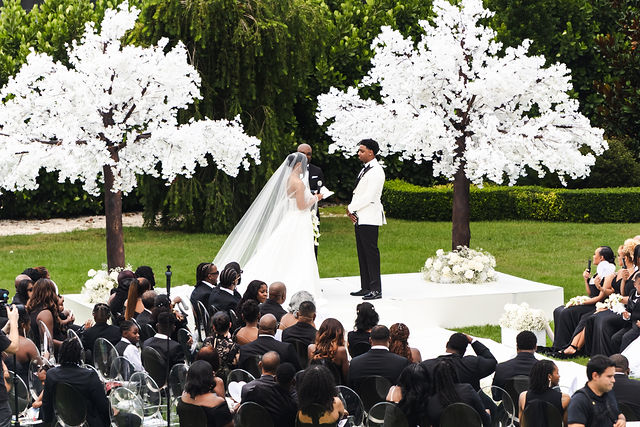 Chrispin and Netania standing beneath white flowering trees during their ceremony