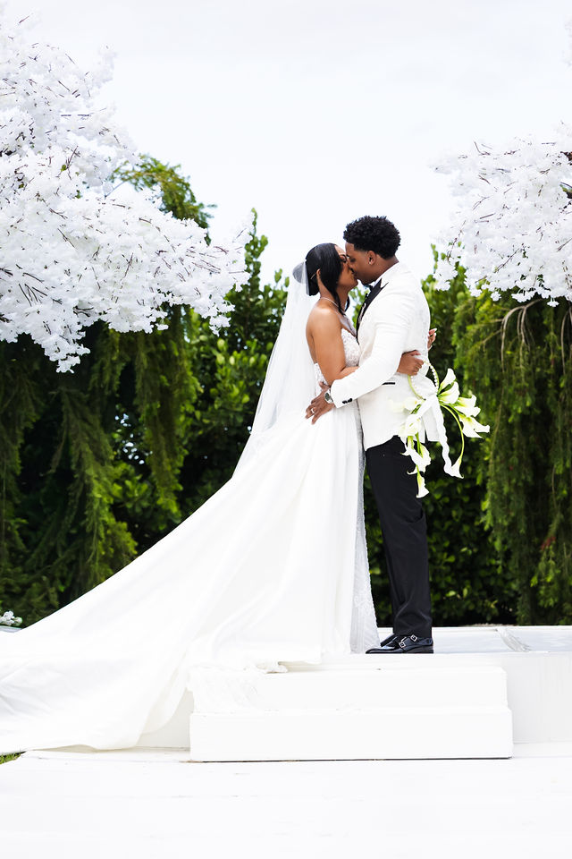 Newlyweds kissing at the all-white ceremony altar