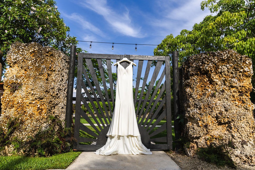 Sharlena’s wedding dress hanging at ElopeWe’s garden gate