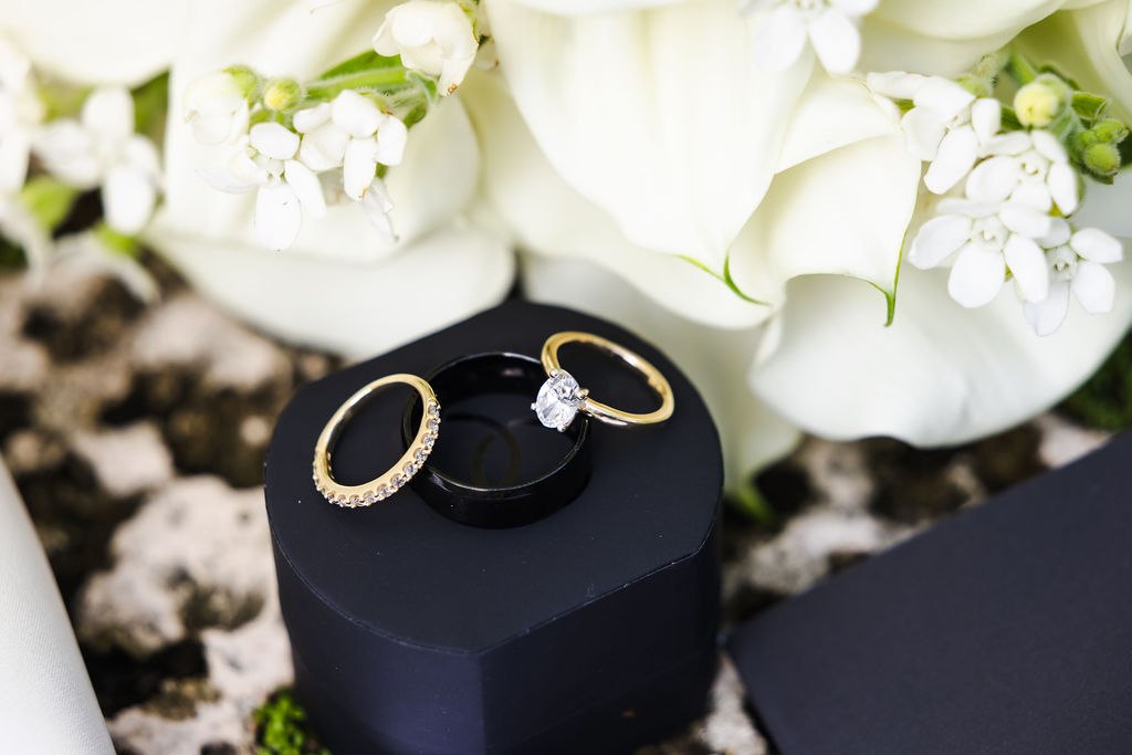 Wedding rings resting in a dark blue ring box with white flowers