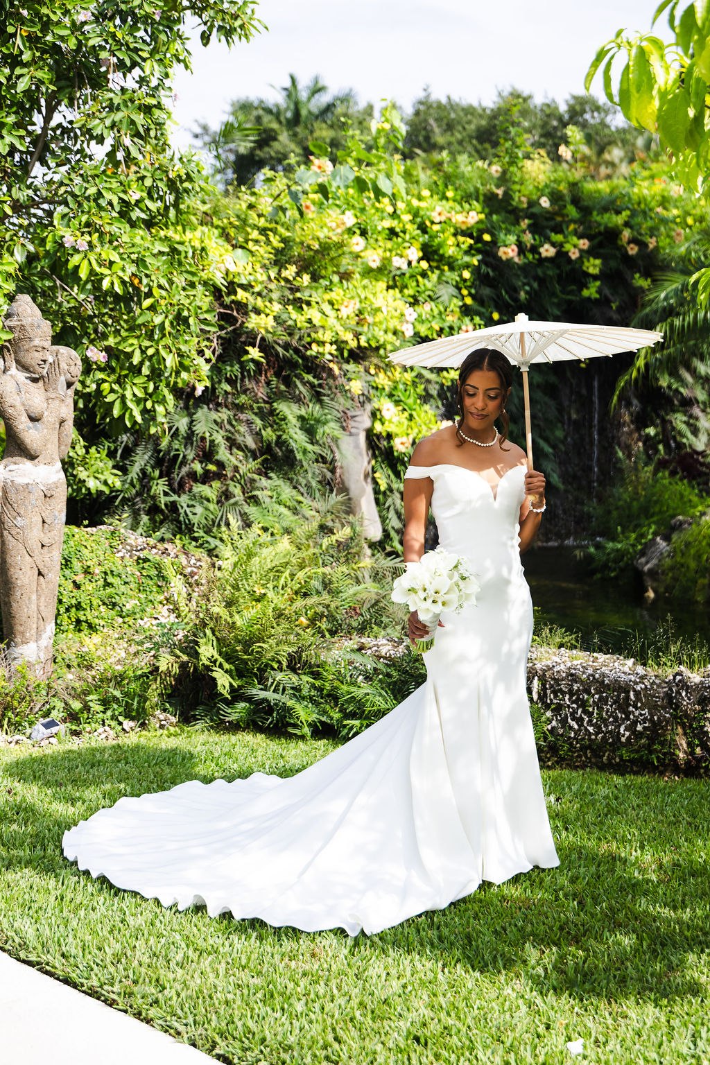 Sharlena holding a white parasol in the garden