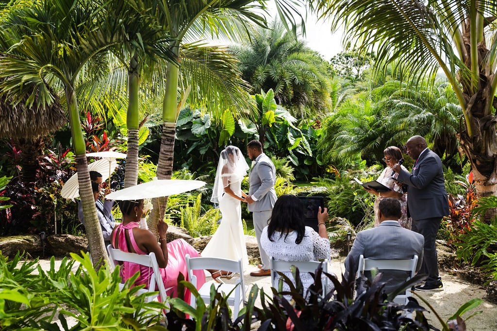 Adrian and Sharlena exchanging vows with guests seated in the garden