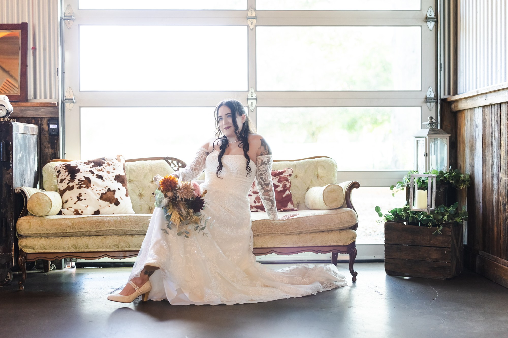 Nina with her bouquet beside a vintage sofa inside Rockin H Ranch