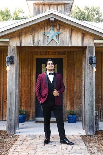 Ayrton in a burgundy jacket outside a rustic wooden ranch building