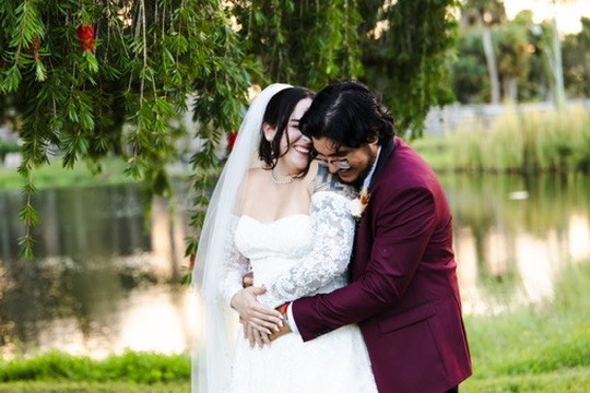 Nina and Ayrton laughing together beneath the trees beside the pond