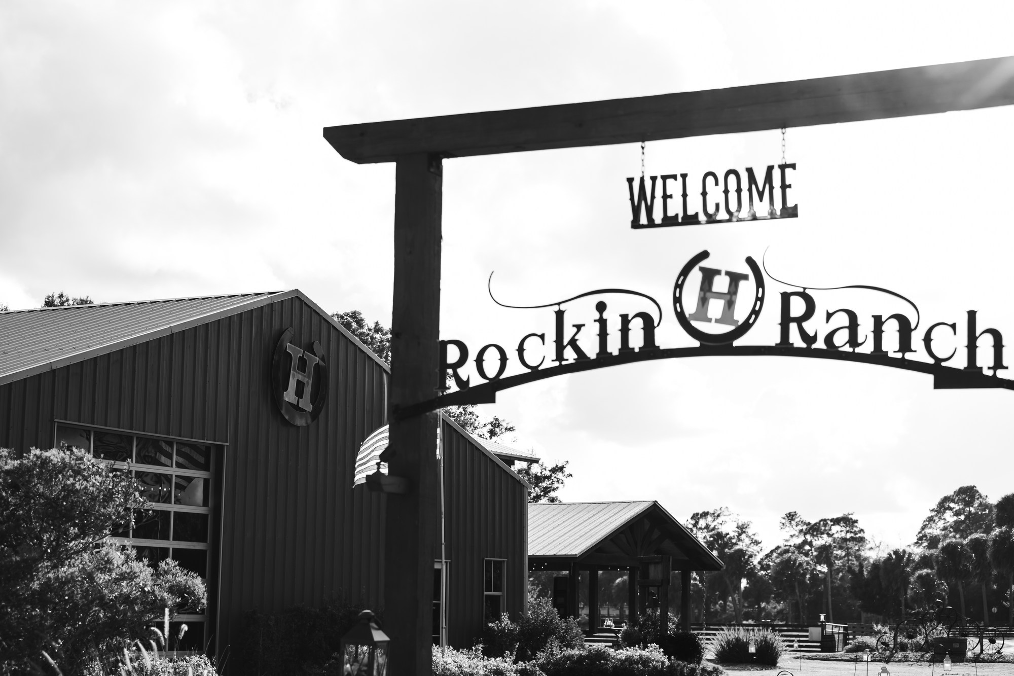 Black-and-white photograph of the Rockin H Ranch welcome sign and barn