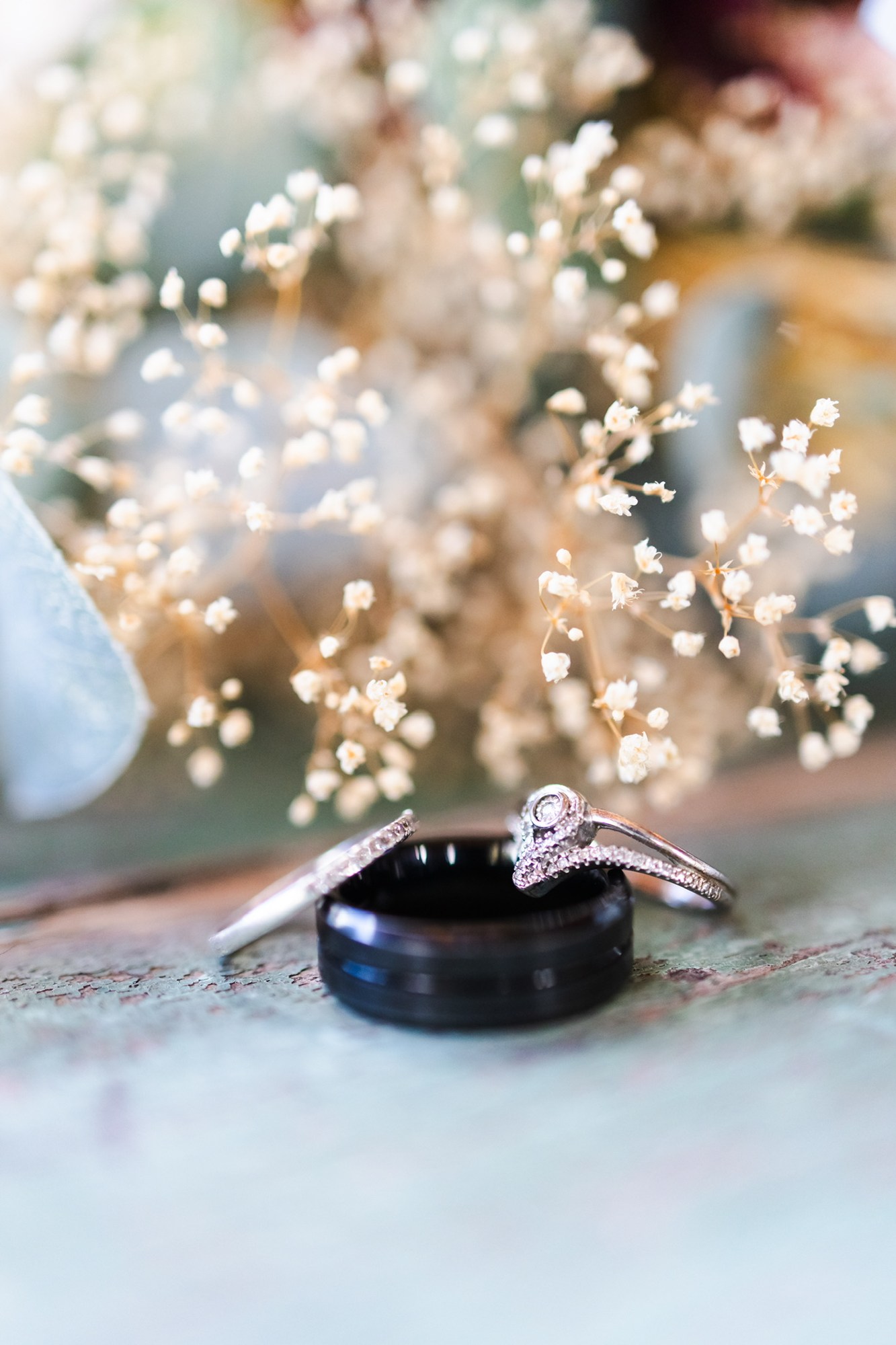 Wedding rings with dried flowers on a weathered green tabletop