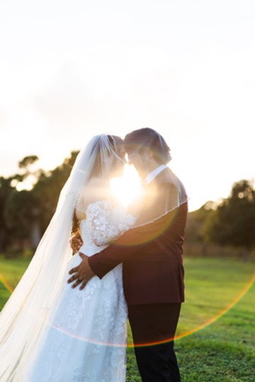 Sunlight shining between Nina and Ayrton during a sunset kiss