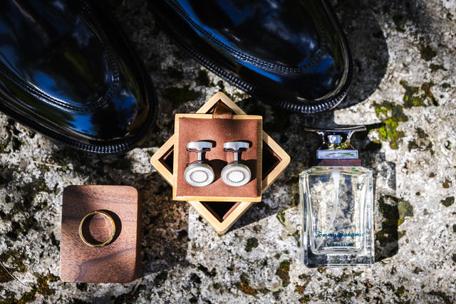 Wedding rings, fragrance and cuff links on coral stone