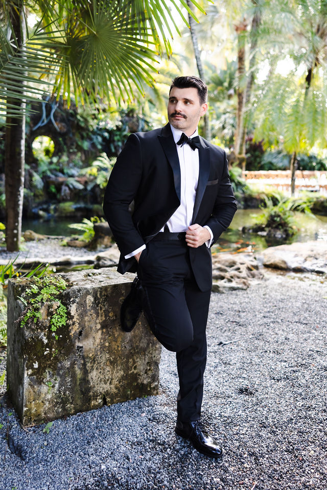 Groom portrait among palms and coral stone